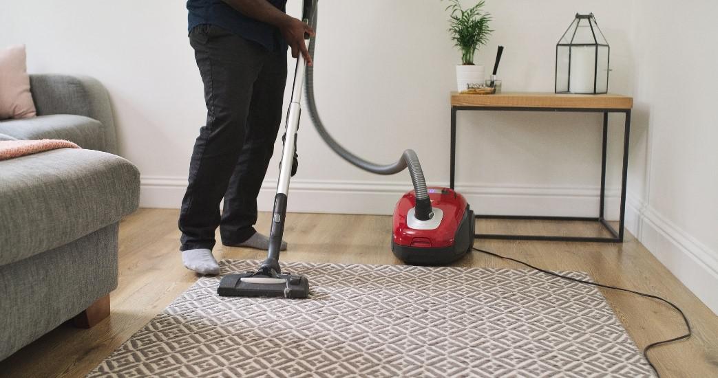 man cleaning carpet using vacuum cleaner